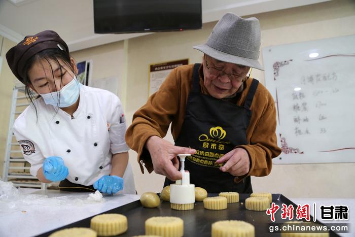 當日，受邀參加活動的臺胞臺屬代表、兩岸婚姻及子女、在甘臺商代表等歡聚一堂。圖為77歲的在甘臺胞潘天鑒制作月餅。九美旦增 攝